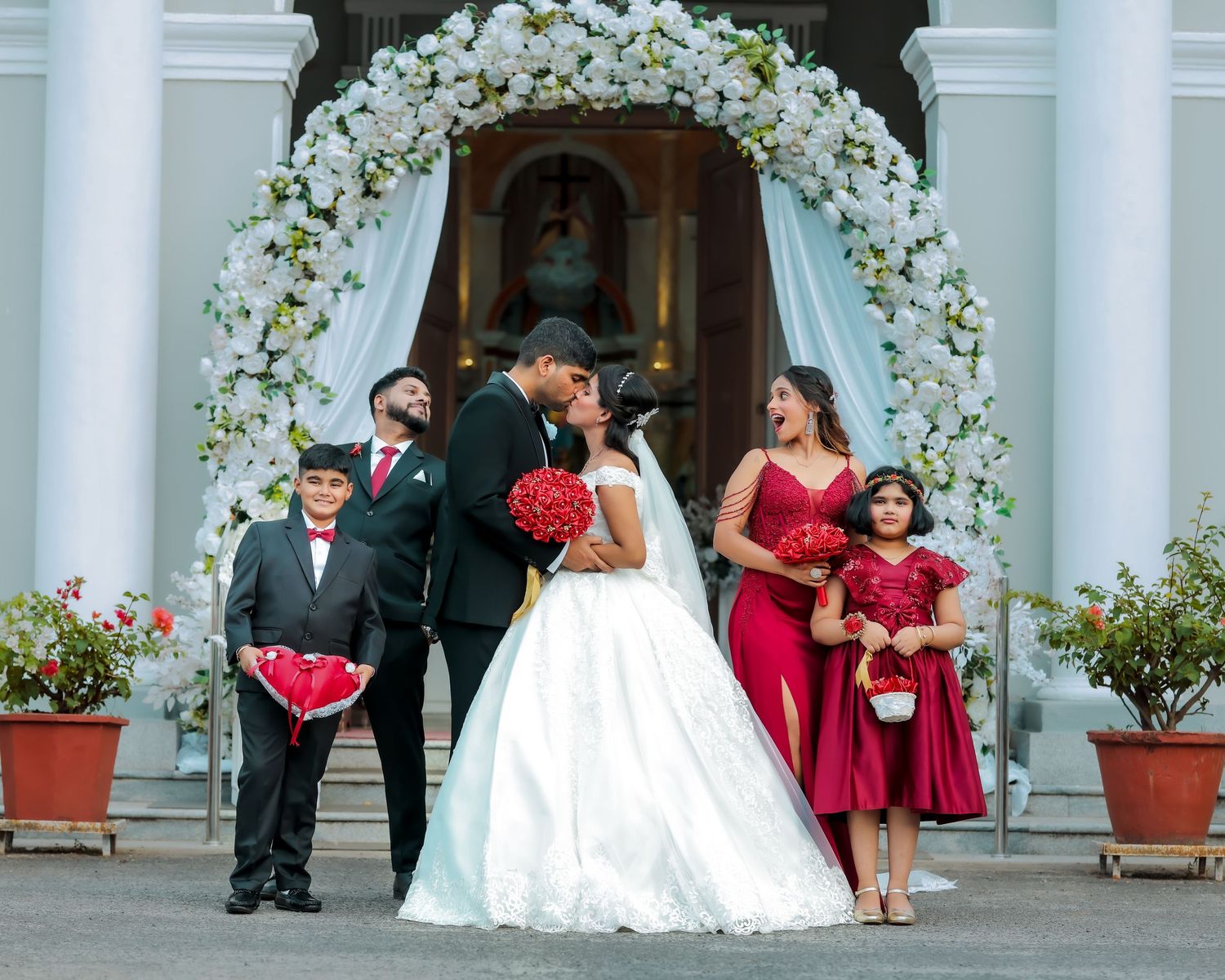 Bride and groom posing with family and wedding guests outside a decorated venue