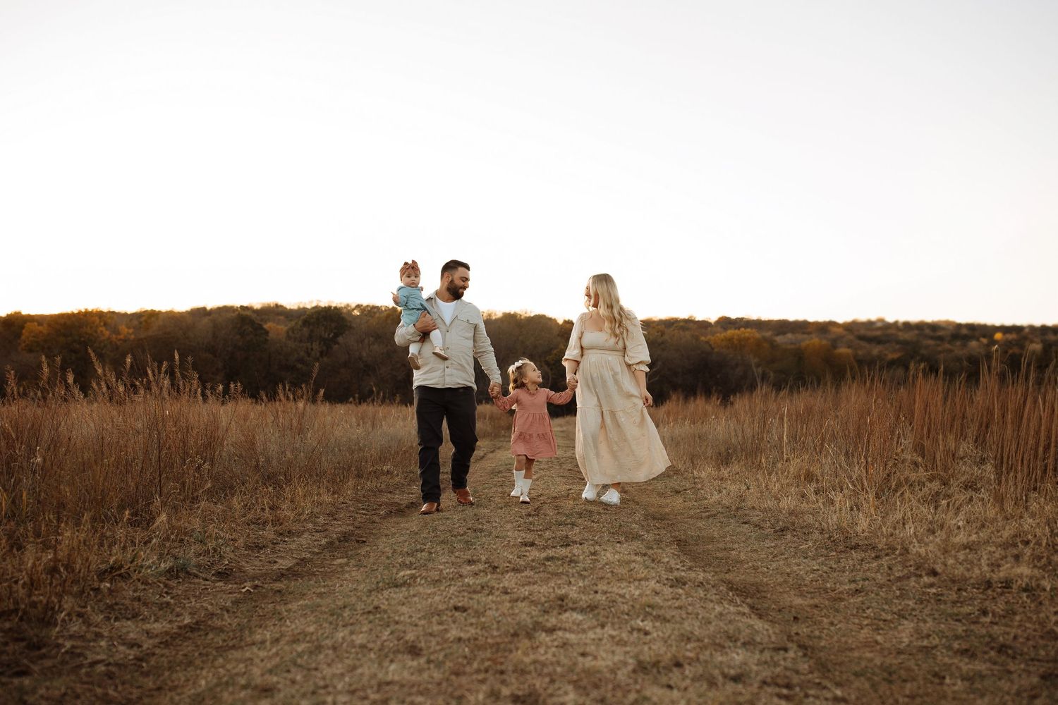 A family walks together hand in hand on a nature path at golden hour. Tulsa family photographer