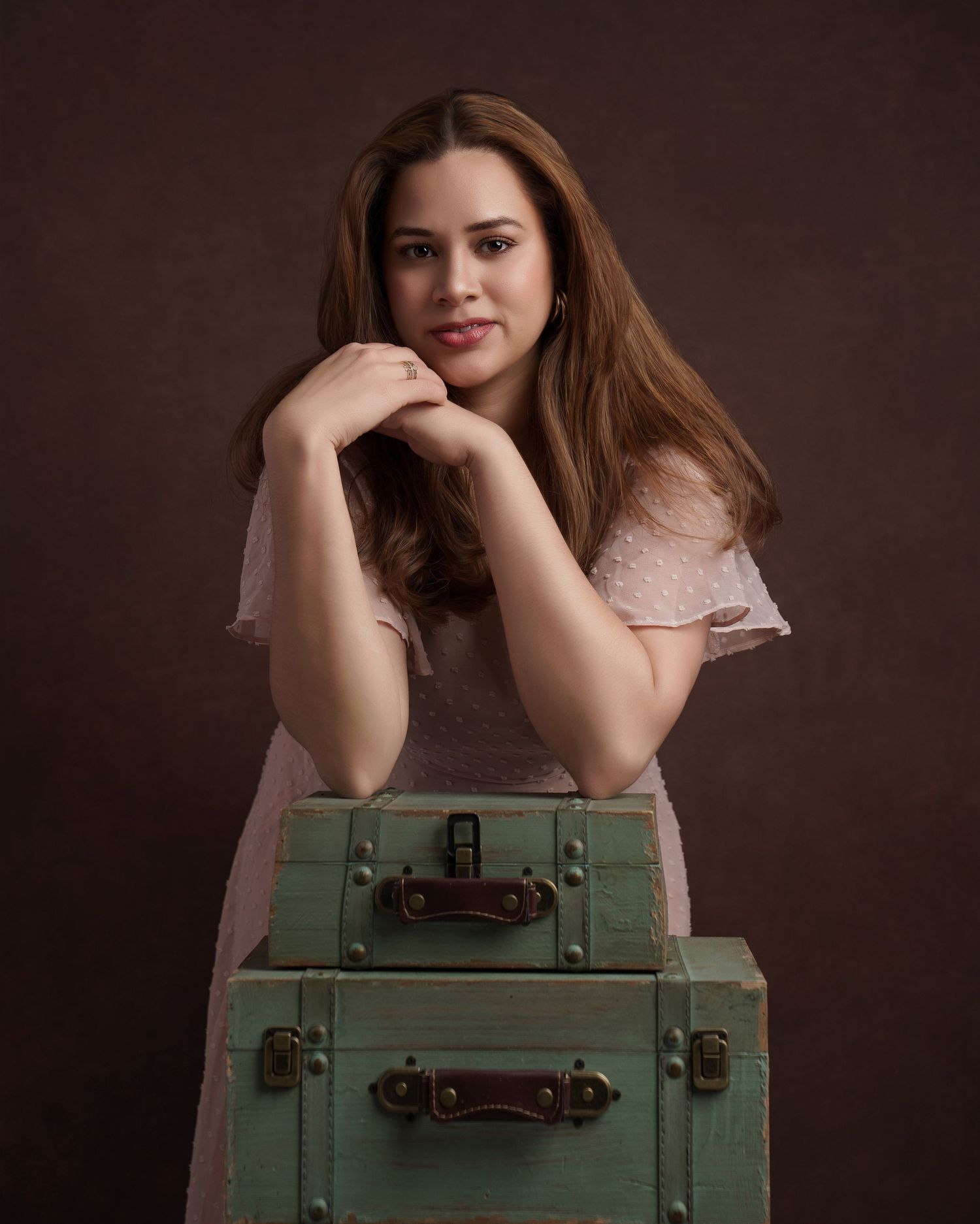 Portrait with vintage green suitcases against brown background.