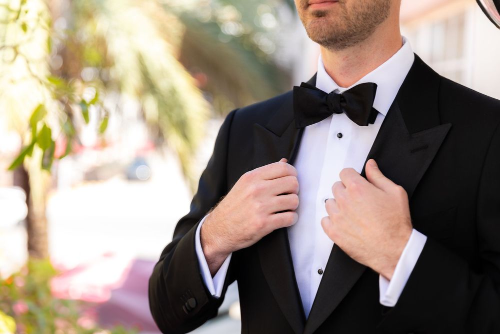 Detail shots of groom adjusting his bowtie and tuxedo before the ceremony.
