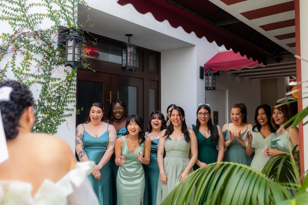 Bridesmaids in seafoam green dresses lined up on a Mediterranean-style patio.