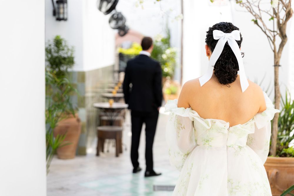 A romantic outdoor wedding ceremony setup with lanterns, white walls, and potted plants along a walkway.