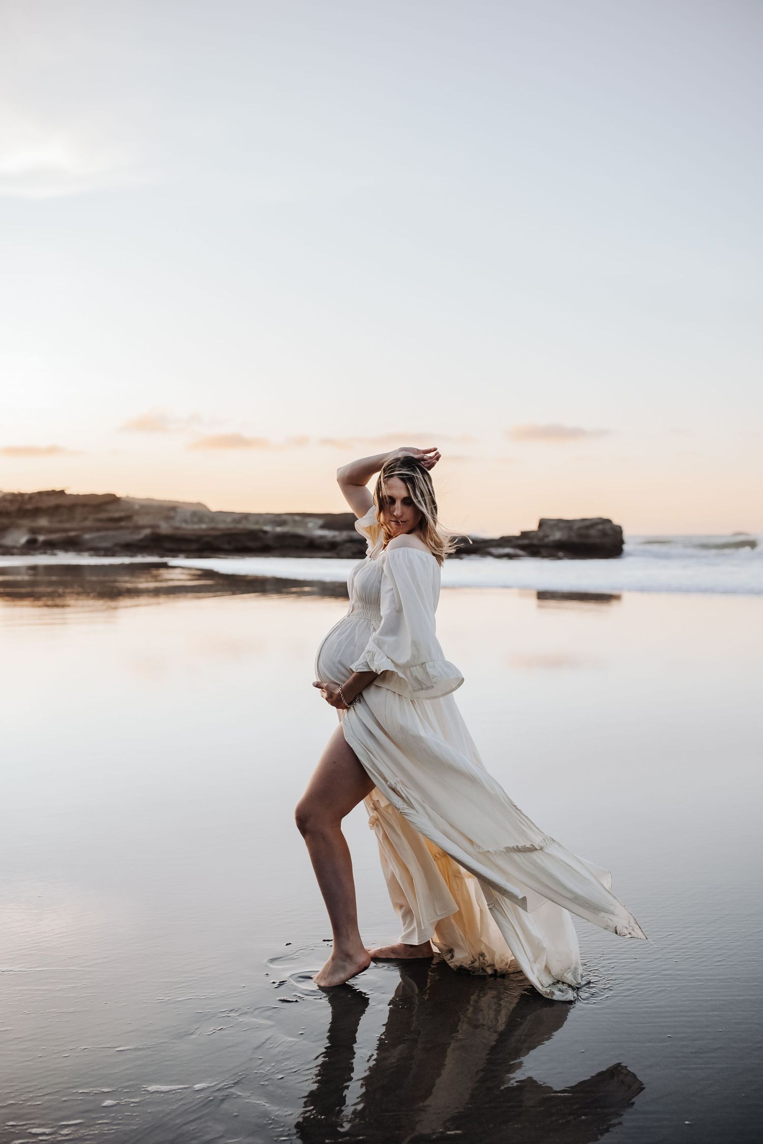 Maternity portrait of expectant mother on golden-hour beach Westport NZ