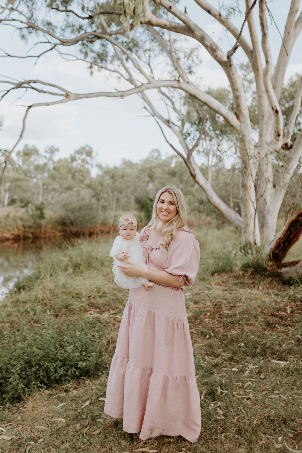 motherhood session in mount isa. mother and daughter pose on fallen over tree