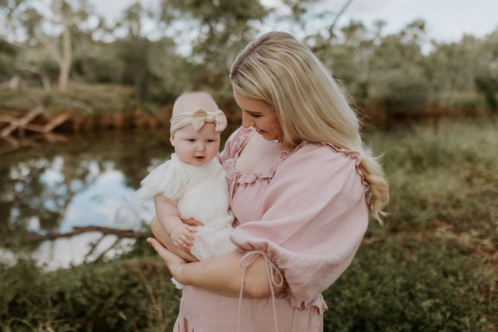 motherhood session in mount isa with mother and daughter posing with river behind them