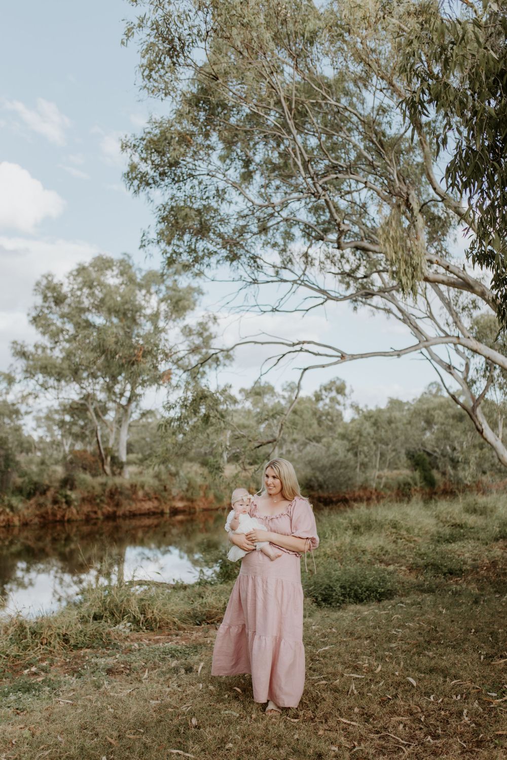 motherhood session in mount isa, mother and daughter walk with river in background