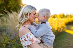 A tender moment is shared between two people in a sunlit field with golden light and tall grass in the background. NJ Family Photographer