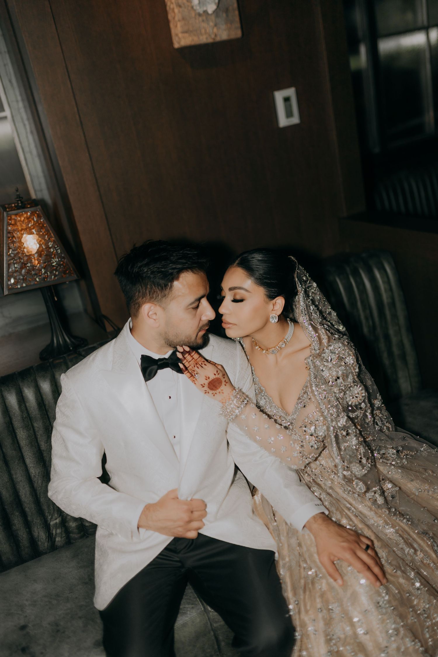 Romantic couple in formal attire sharing an intimate moment on leather seating.
