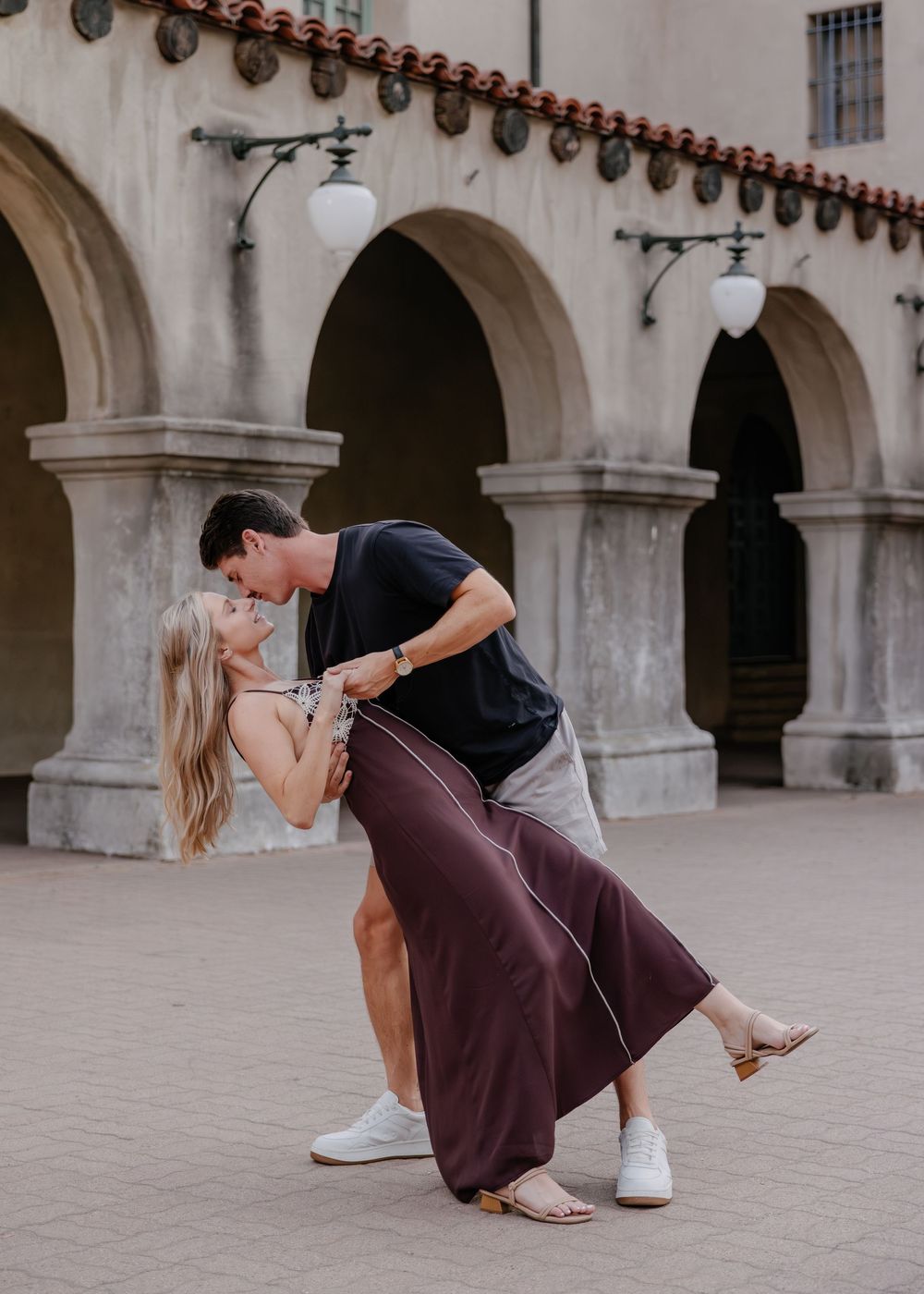 Dance-like poses in a historic courtyard with stone arches and lanterns creating a romantic ambiance.