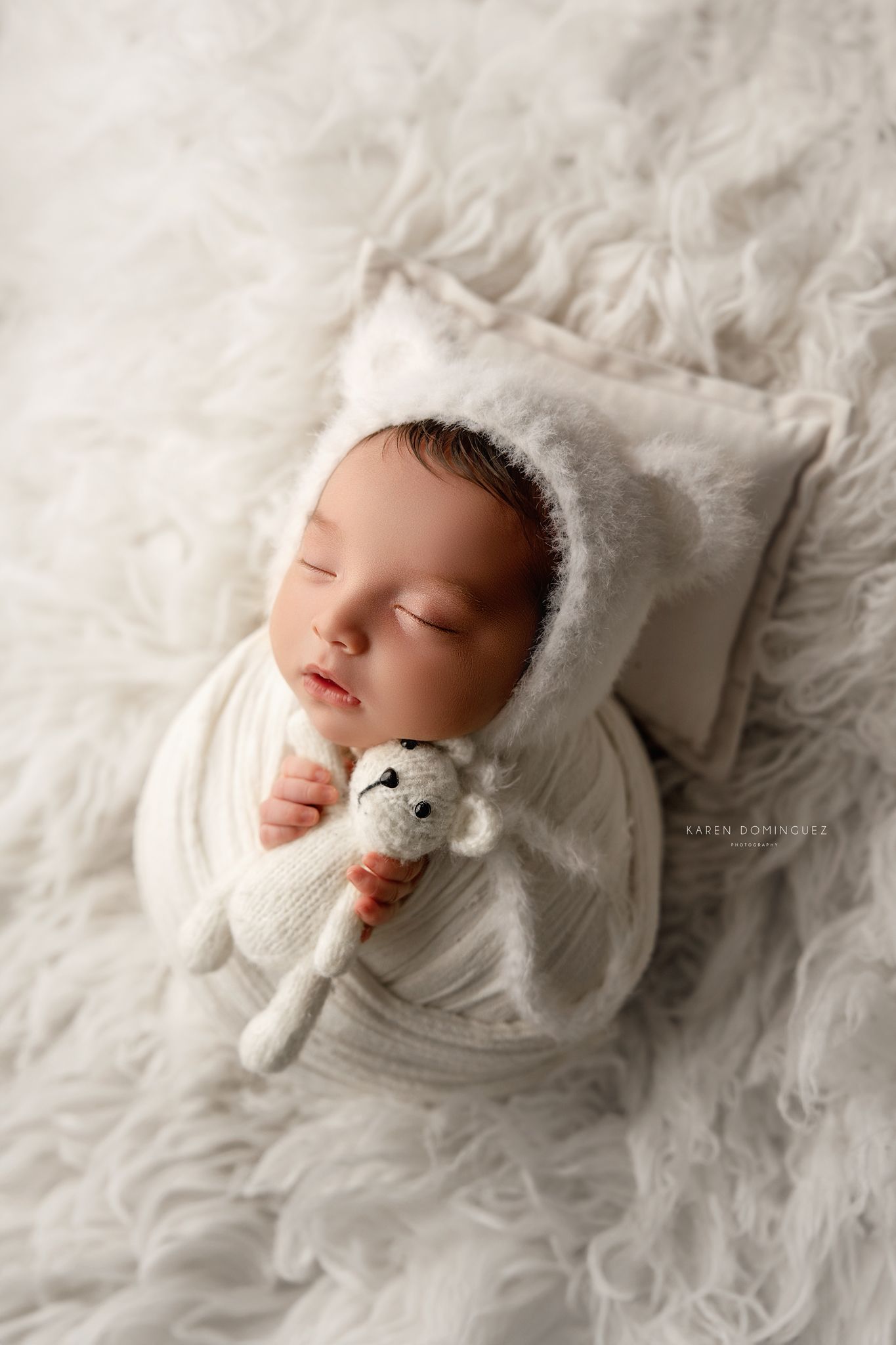 Top-down view of sleeping newborn surrounded by vintage photographs in sepia and black-and-white tones.