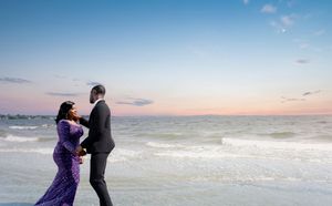 Romantic beach photoshoot at sunset with waves crashing in background.