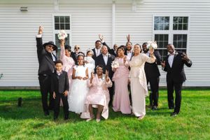 Large group celebration photo outside white church building with wedding party and guests.