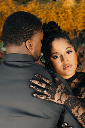 Romantic couple in formal wear embrace against autumn backdrop.