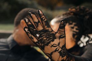 Close-up details of black lace against formal attire in natural lighting.
