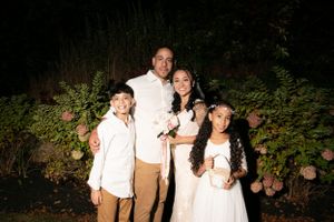 Family portrait taken outdoors at night with garden foliage in background.