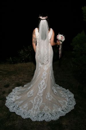 Back view of a bride in an elegant lace wedding gown with a long train.