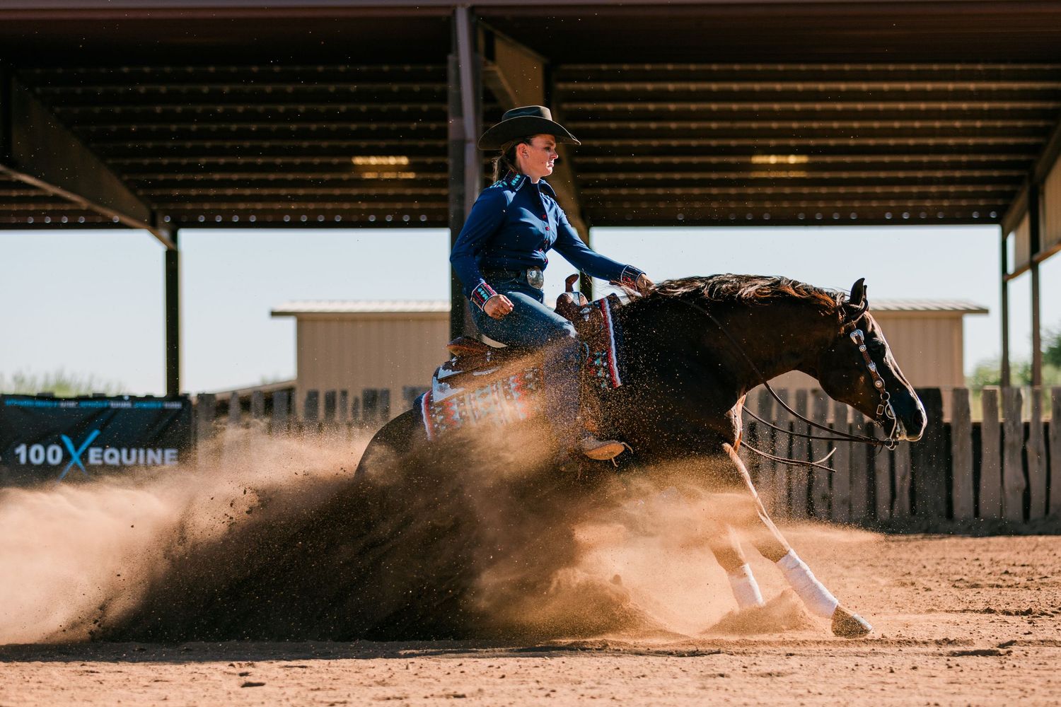 Equestrian rider kicks up dust while barrel racing in an outdoor arena during competition.
