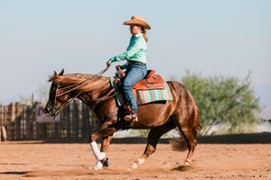 Barrel racing horses and riders compete at high speeds in a dusty outdoor arena.