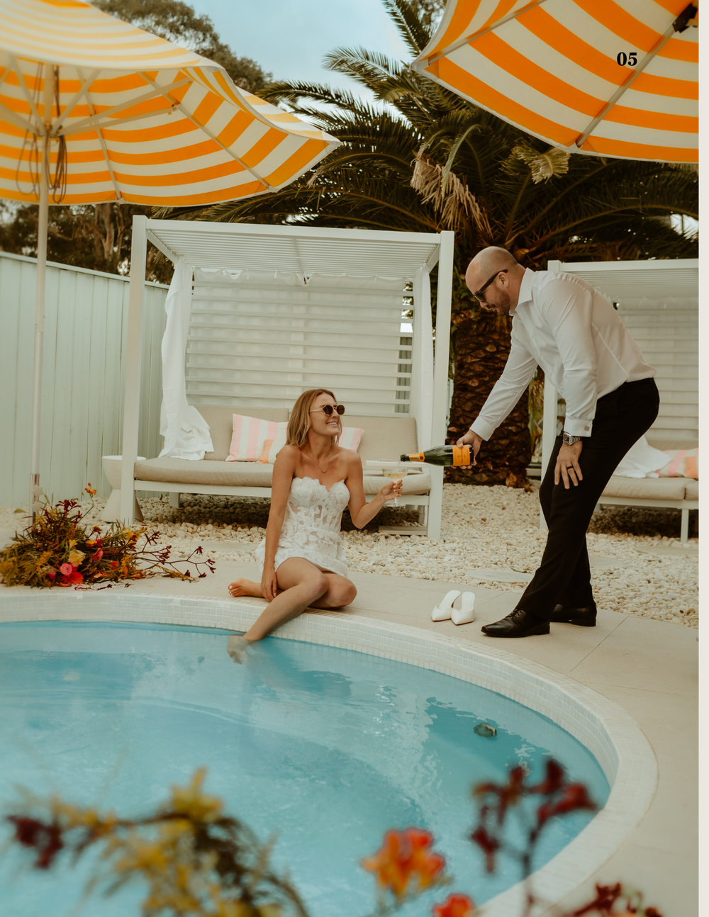 A romantic poolside scene with orange striped umbrellas and white cabanas at a luxury resort.