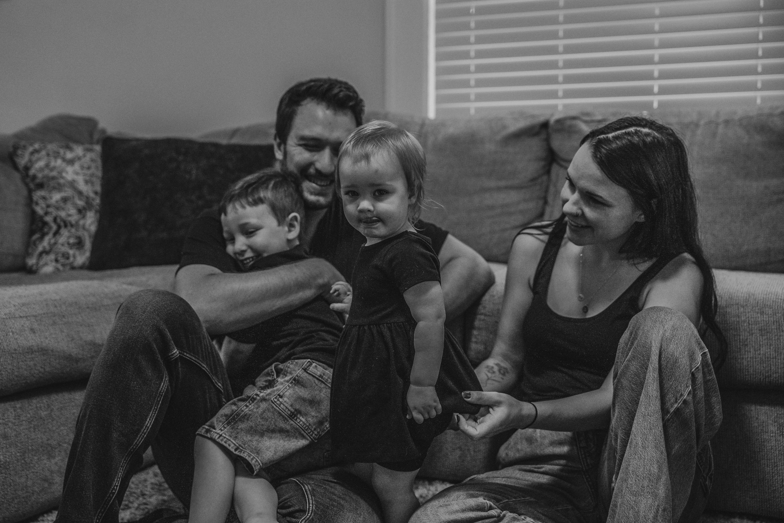 Black and white portrait of family relaxing together on living room sofa.