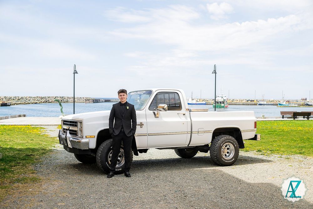 A classic white pickup truck parked by the waterfront with a person standing beside it in Maine.