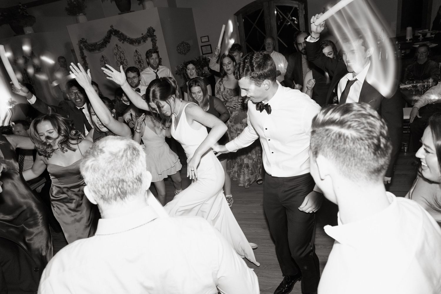 People dancing and celebrating at a lively wedding reception party on a crowded dance floor.