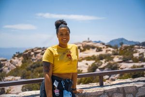 Person in yellow shirt enjoying panoramic views from desert mountain viewpoint.