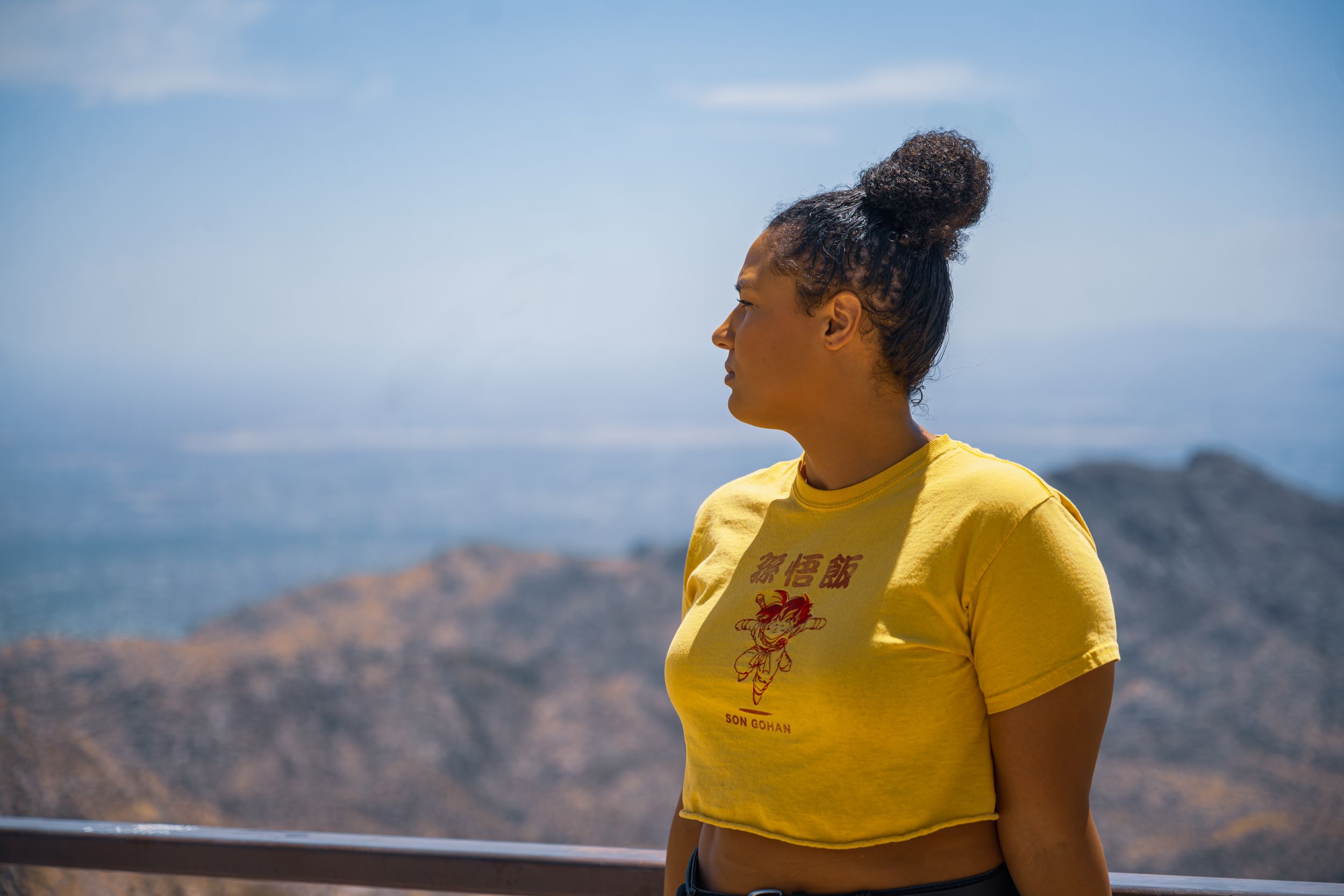 Person in yellow shirt gazing at desert mountain panorama on sunny day.