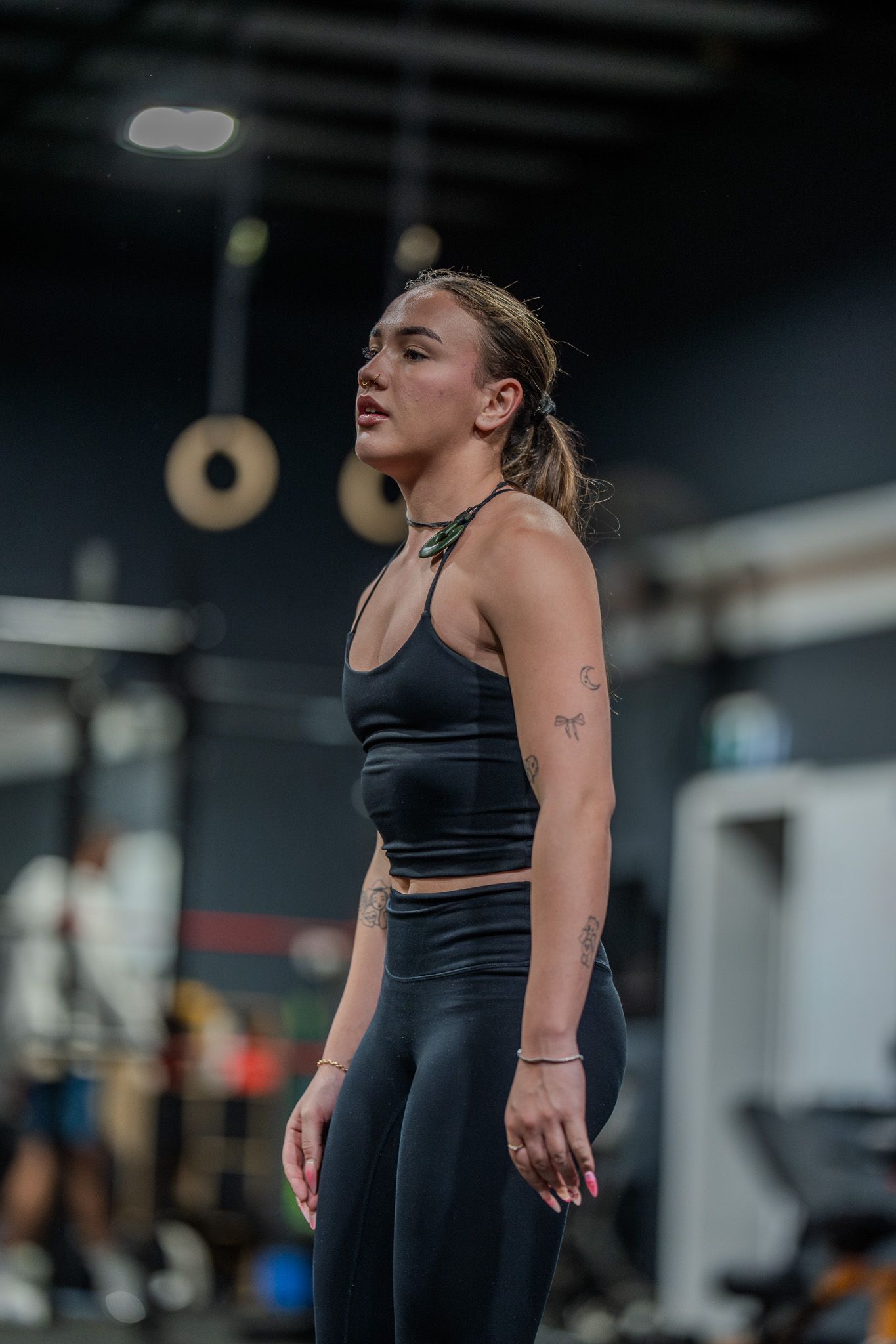 Athletic person in black workout attire takes a breath during intense training session at a gym.