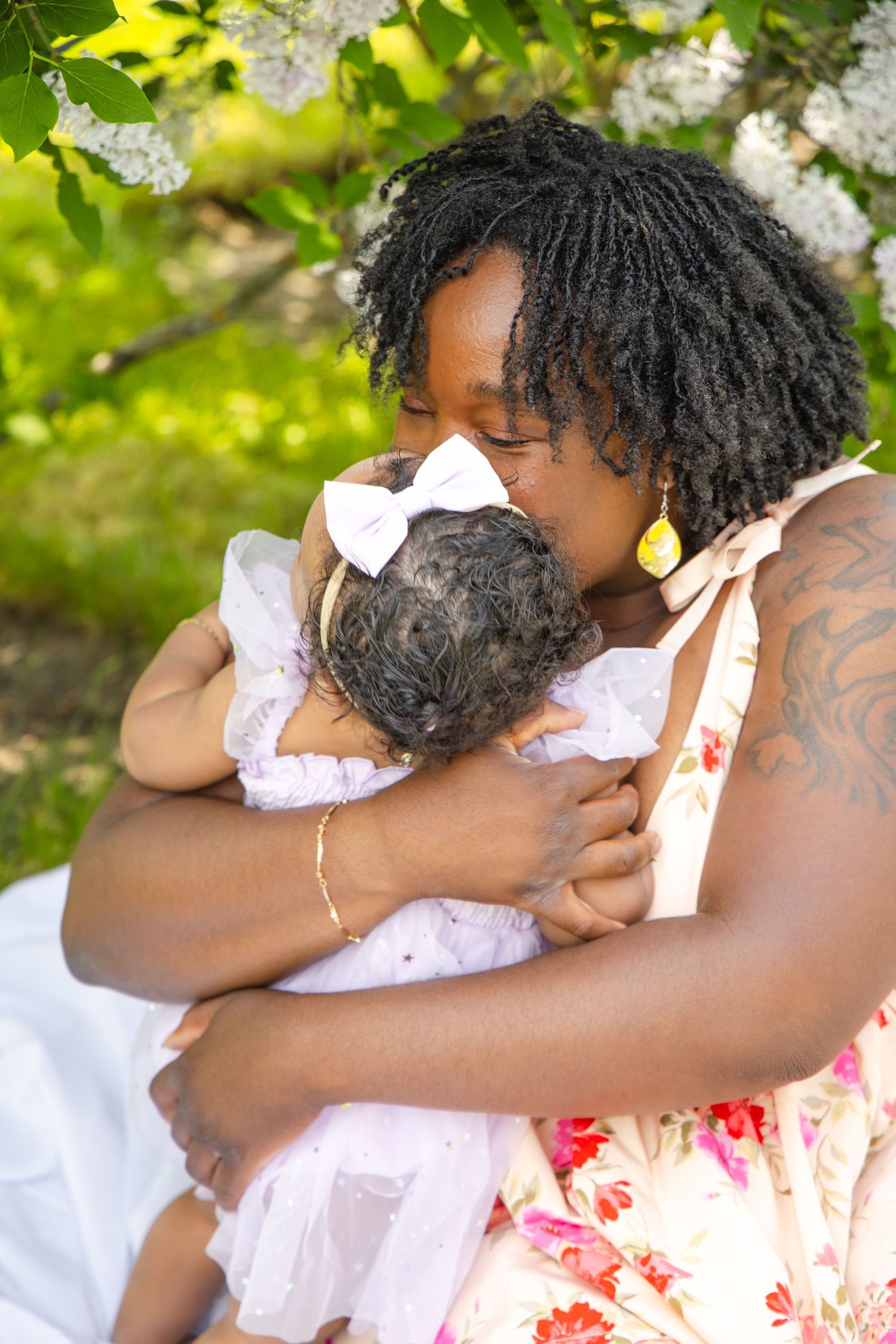 Couple in white summer outfits sharing an intimate embrace under bright green foliage.