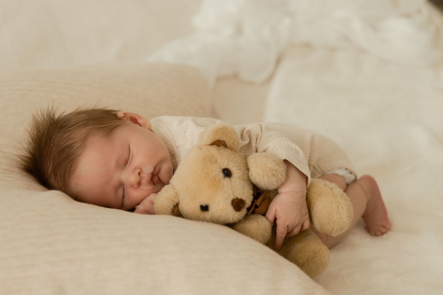 In-home newborn photo of baby snuggled up with teddy bear during cozy session in Kennewick WA