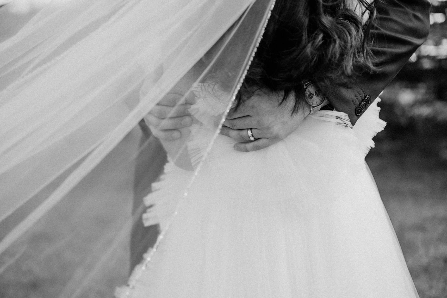 Close up detail of bride's veil and ring in black and white.