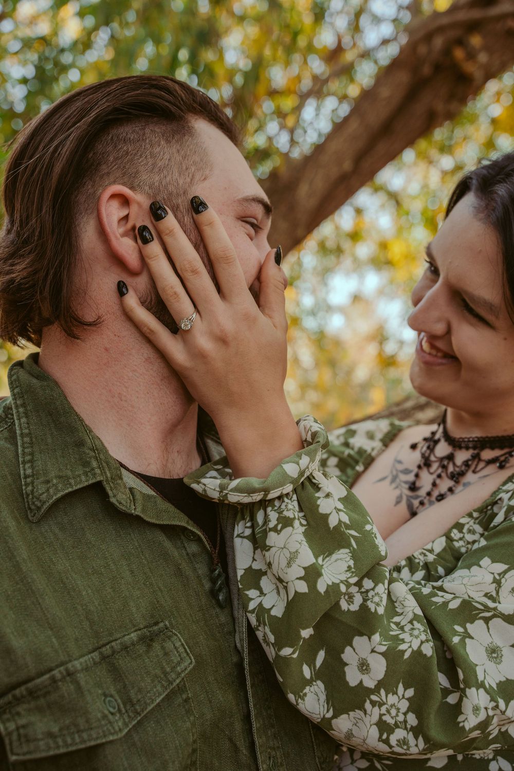 A romantic couple sharing intimate moments outdoors with autumn trees and soft lighting in the background.