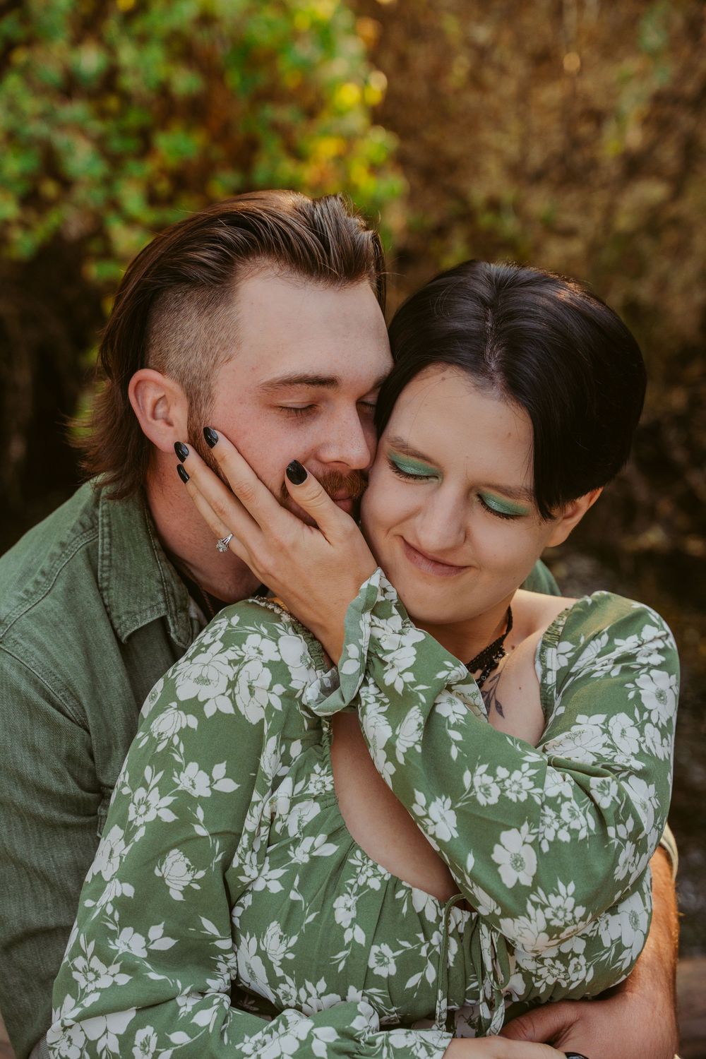 Romantic couple in green outfits sharing an intimate moment outdoors with soft natural lighting and autumn background.