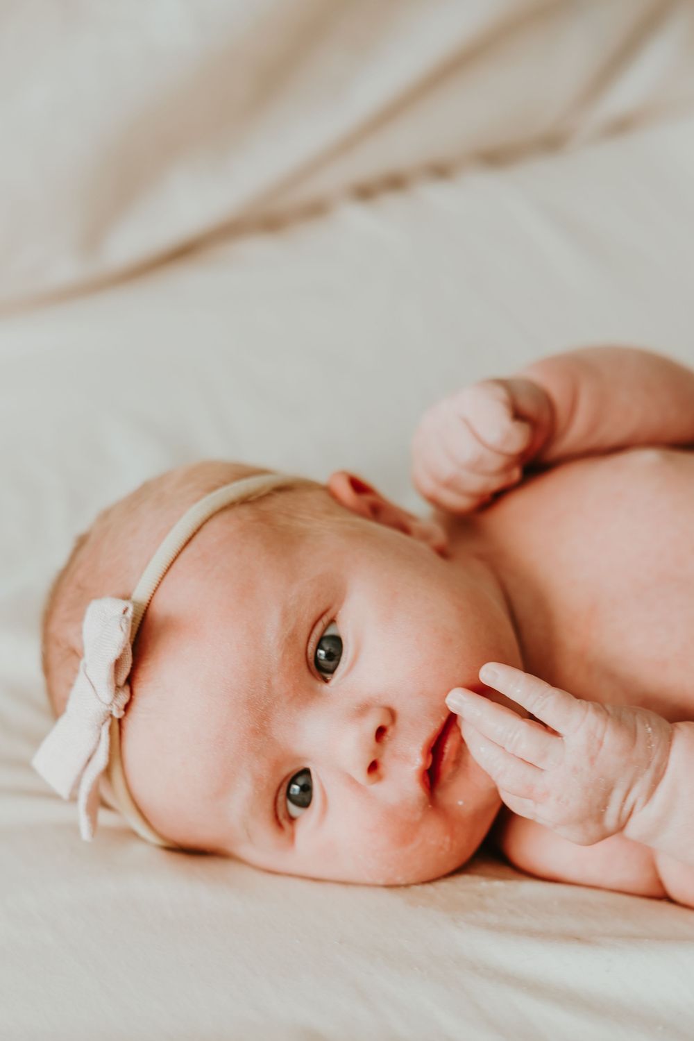 A sweet baby lying on soft white bedding, with gentle lighting creating a serene and peaceful mood.