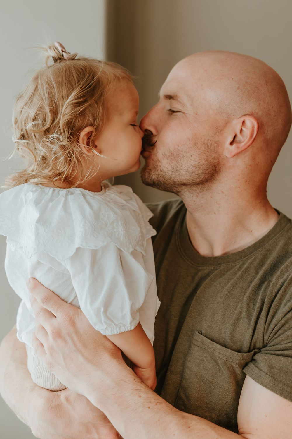A tender moment between parent and child as they share an affectionate nose-to-nose touch while wearing casual attire.