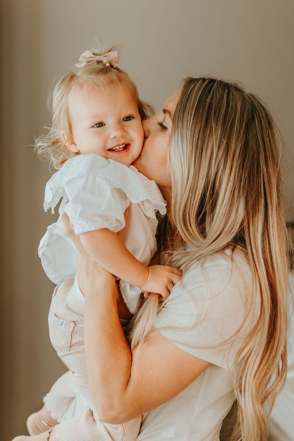 A tender moment between parent and child, both wearing white, shown in a series of affectionate candid shots.