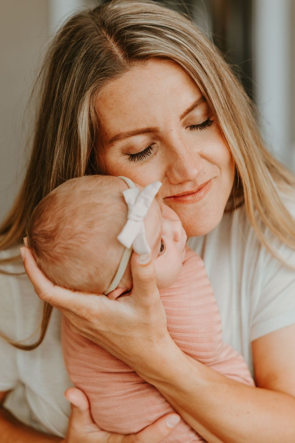 A tender moment captured as parent and newborn share a gentle nuzzle in warm lighting.