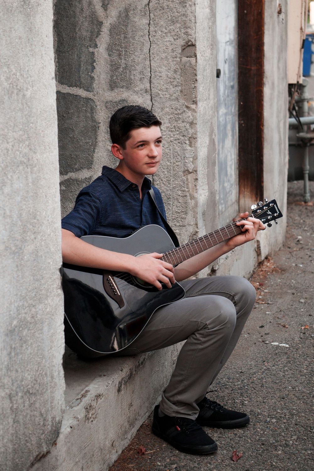 Lifestyle senior photo of teenage boy playing acoustic guitar during casual outdoor session