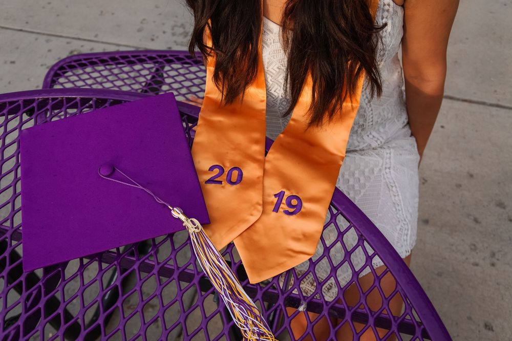 Close-up of purple graduation cap and orange 2019 sash on bench during senior session Hanford High School