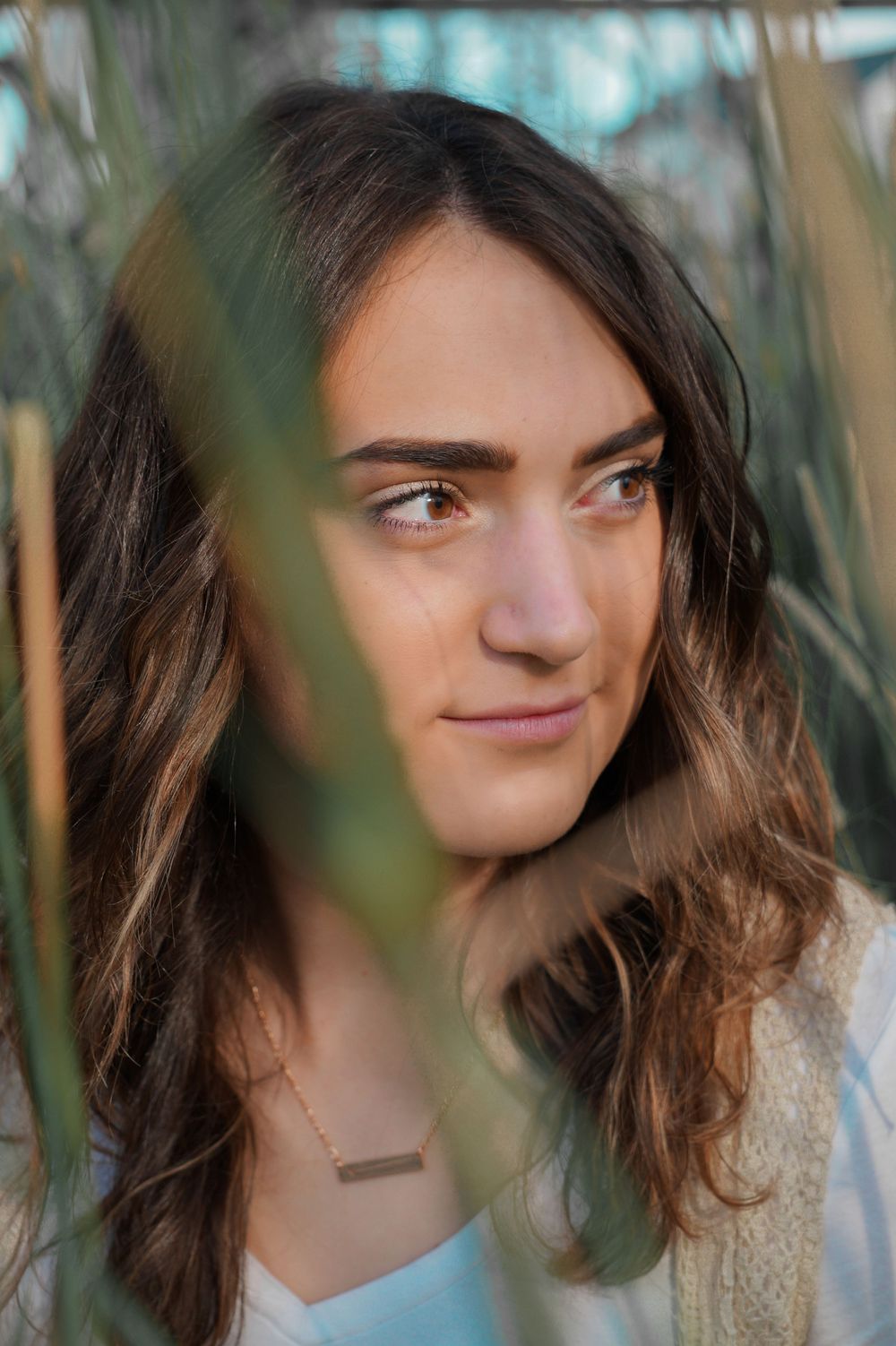 Natural light senior portrait of girl looking off-camera through tall grass during outdoor session
in Eastern WA