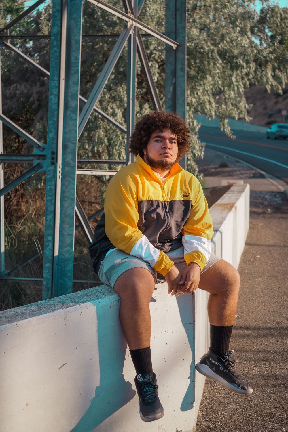 High school senior wearing yellow jersey sitting on bench during casual senior session at outdoor location in Kennewick WA