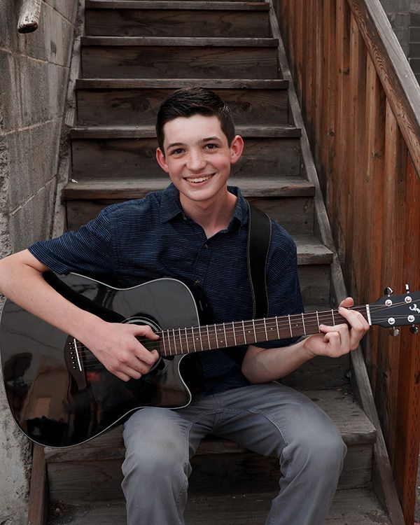 Senior boy sitting on stairs with guitar during lifestyle senior session in downtown Richland WA