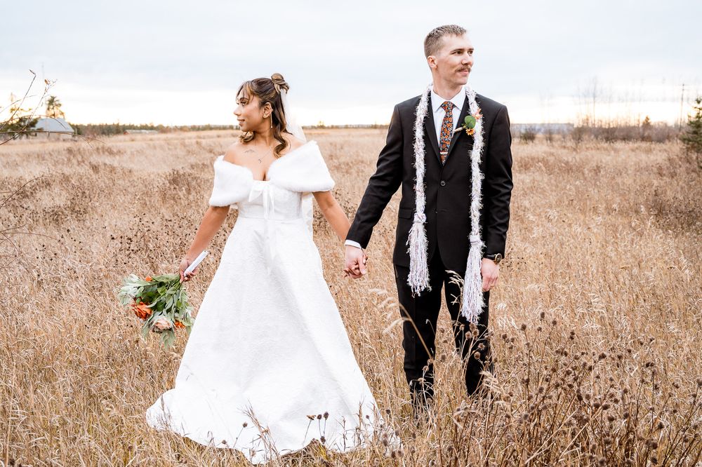 Newlywed couple shares intimate moments in a serene field with autumn-toned florals and natural lighting.