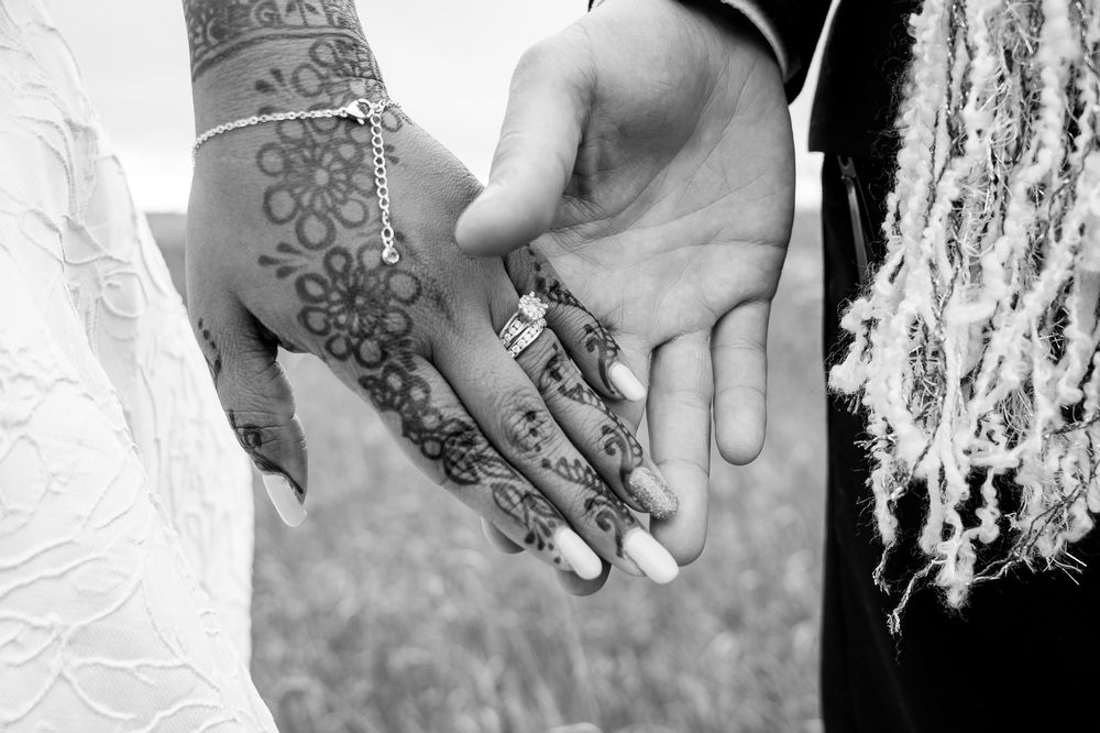 Black and white close-up photo montage of wedding details showing rings, hands, and lace decorations.