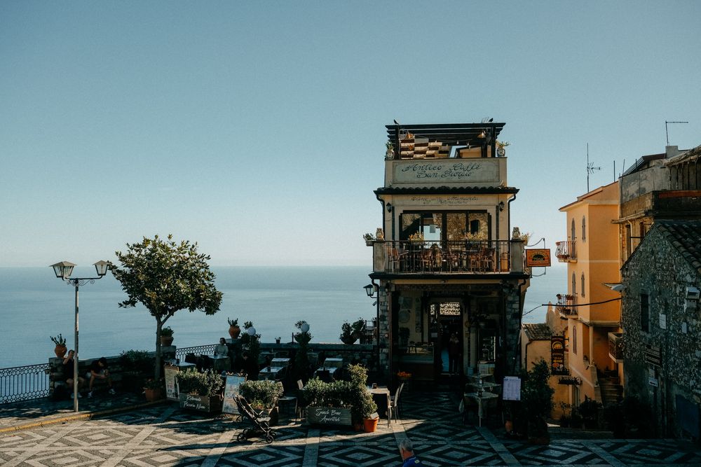 Scenic coastal town view with orange buildings perched on cliffs overlooking the Mediterranean Sea at sunset.