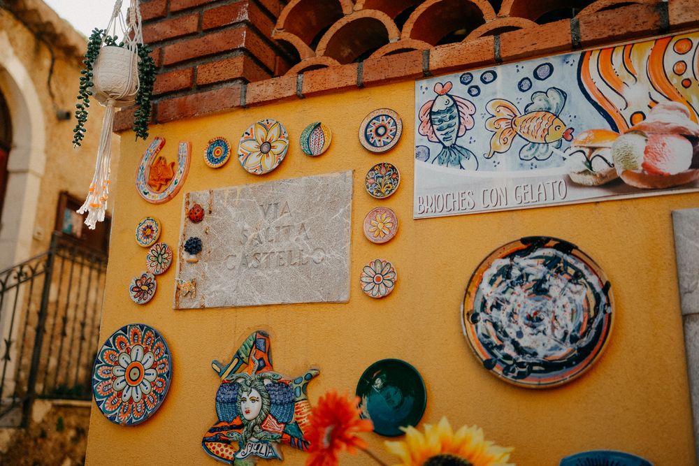 Colorful Mexican pottery and decorative plates displayed on a yellow wall with brick accents and floral ornaments.