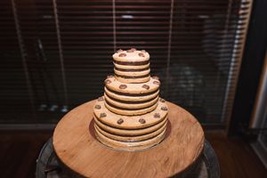Tiered wedding cake with rustic design displayed on wooden table.