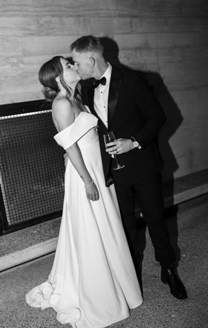 Black and white photo of newlyweds sharing intimate moment at wedding reception.