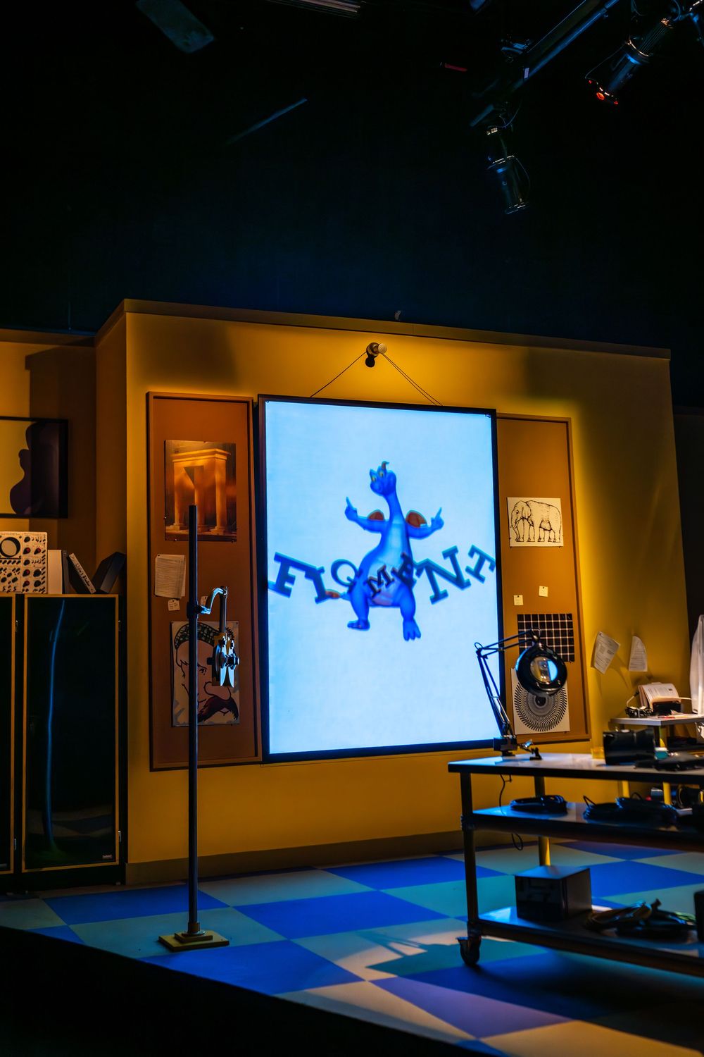 A series of dark room photos showing a blue projection or display screen mounted on a wall with dim ambient lighting. Figment